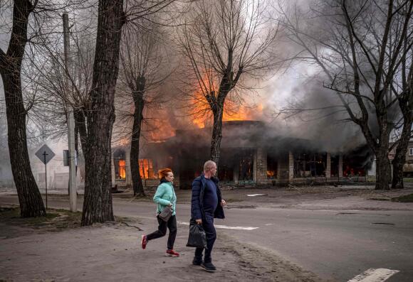 Des habitants courent près d'une maison en feu après un bombardement de Severodonetsk, dans la région du Donbass, le 6 avril 2022. L'Ukraine demande aux habitants de l'est du pays d'évacuer 