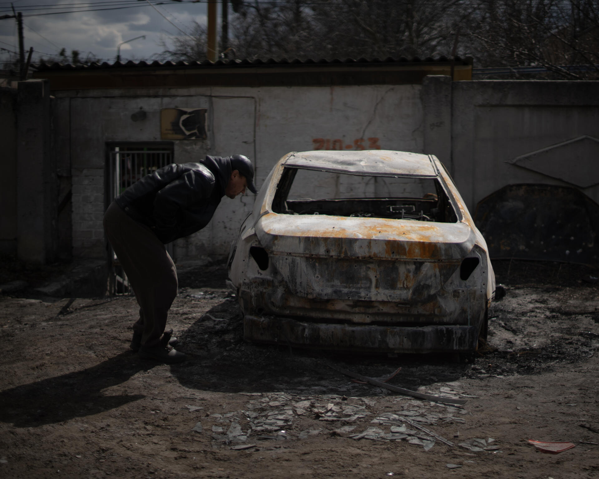 Un homme observe une voiture brulée lors d'un bombardement survenu le 3 avril à Sloboda, faisant 7 morts. Kharkiv, en Ukraine, le 3 avril 2022.