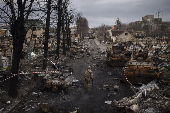 Un militaire ukrainien marche au milieu de chars russes détruits à Boutcha, dans la banlieue de Kiev, en Ukraine, le 6 avril 2022.