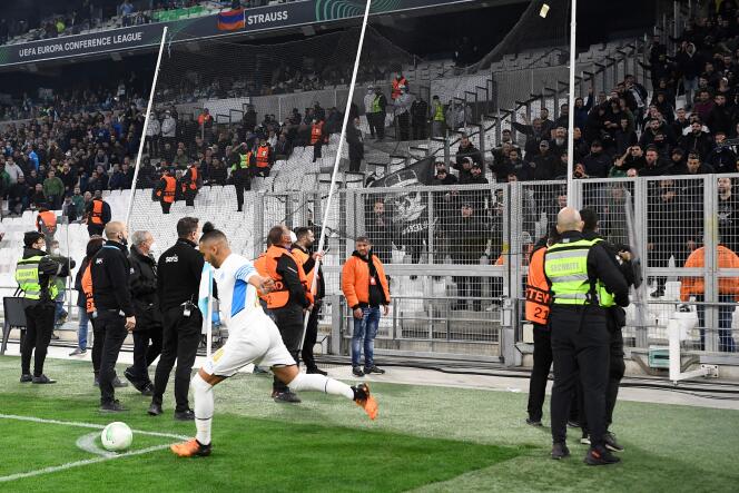 Marseille's Dimitri Payet takes a corner under the protection of security forces, in front of the Greek supporters, on April 7, 2022, at the Vélodrome stadium.