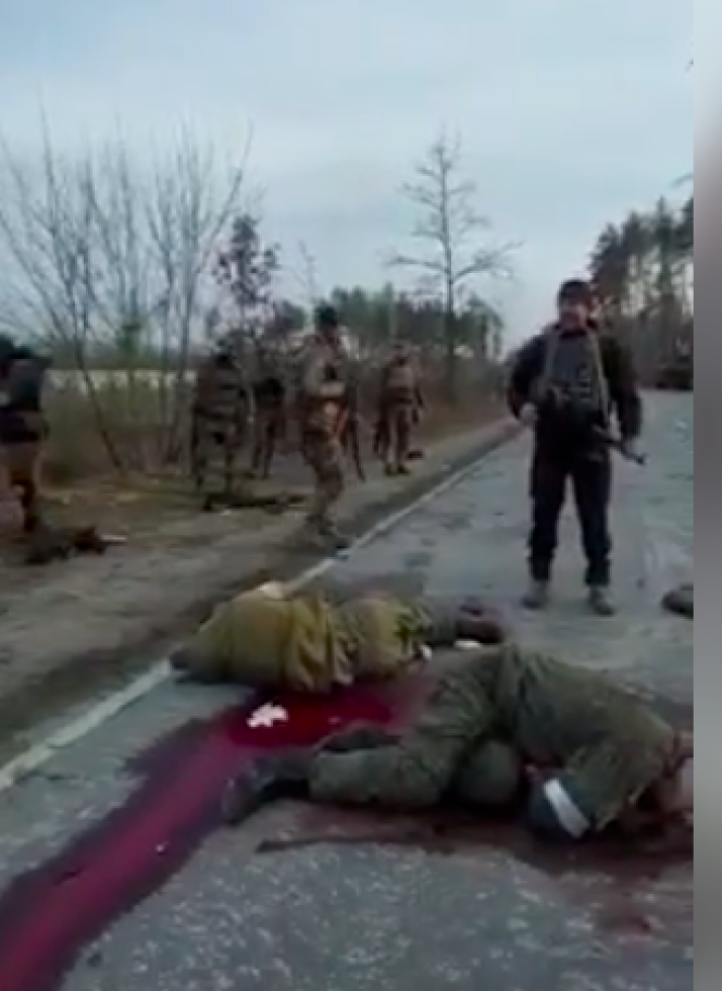 Capture d’écran d’une vidéo authentifiée par le « New York Times » le 4 avril 2022. La scène a été tournée près du village de Dmitrovka, à l’ouest de Kiev, à la suite d’une embuscade sur une route de campagne. Des soldats ukrainiens filment des soldats russes baignant sur la chaussée dans leur sang, et l’un achevé à bout portant. 