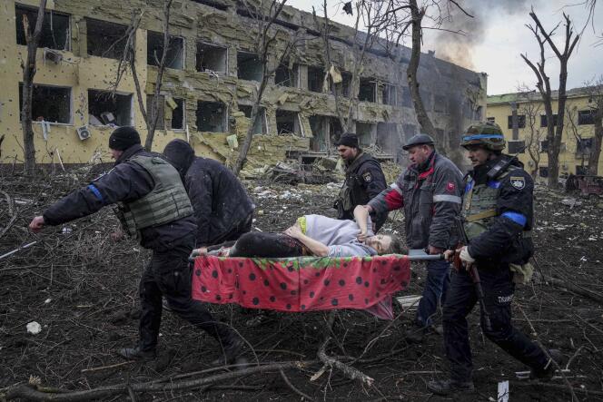 Ukrainian emergency employees and volunteers carry an injured pregnant woman from a maternity hospital damaged by shelling in Mariupol, Ukraine, March 9, 2022.