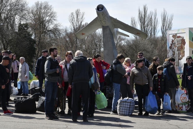 After the bombing of the train station Friday, people wait to board a bus during their evacuation, with a Soviet fighter jet monument right in the background, in Kramatorsk, Ukraine, April 9, 2022.