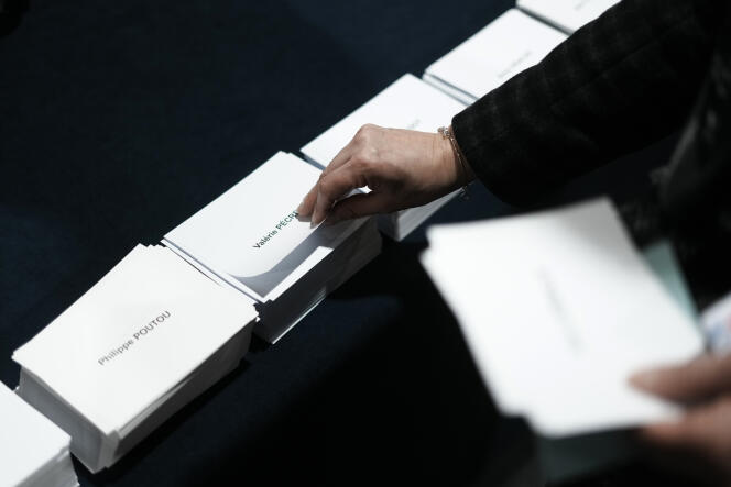 A person takes ballots before voting for the first round of the presidential election, Sunday, April 10, 2022 in Le Touquet, northern France. 