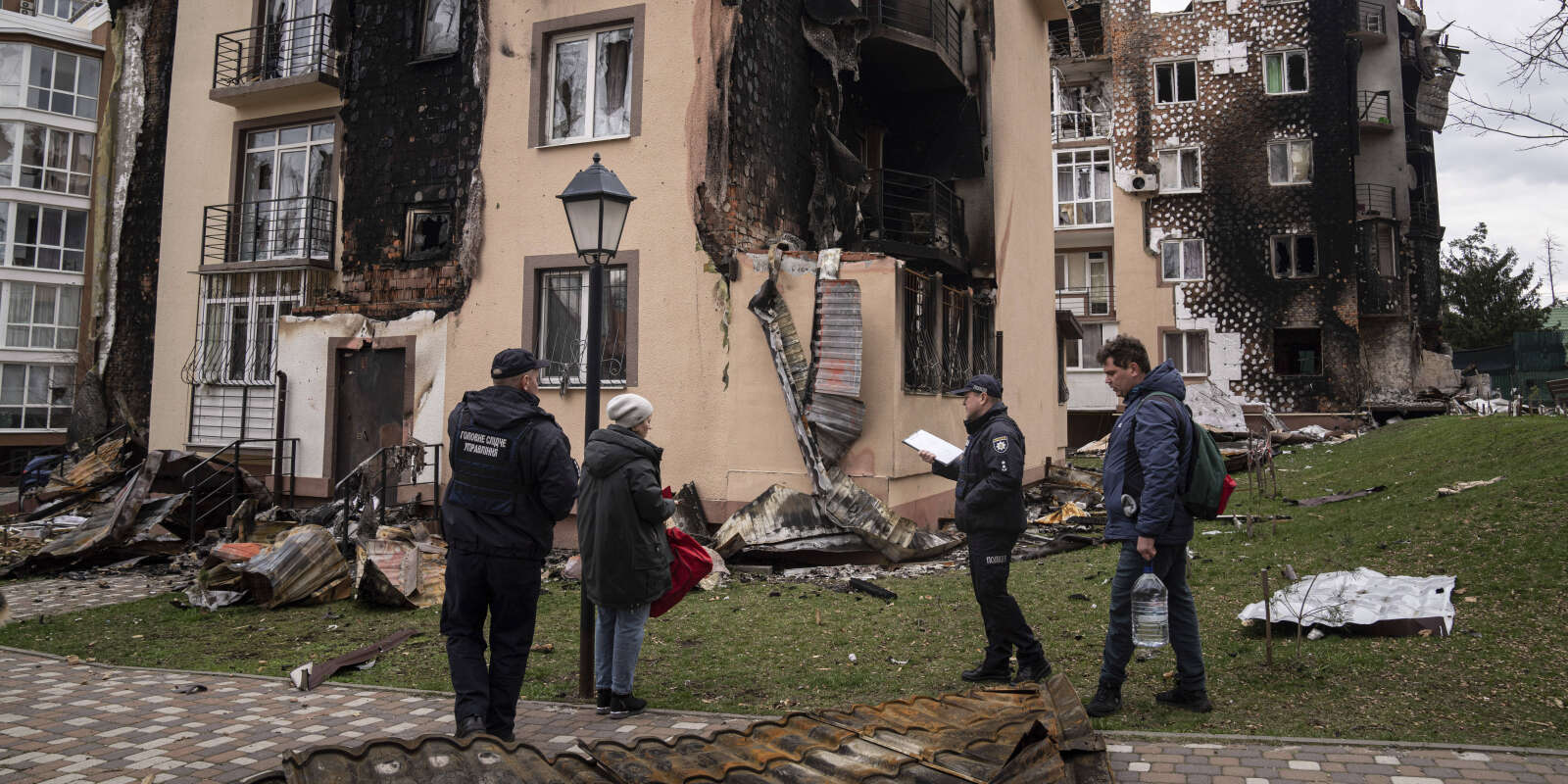 Des policiers constatent en compagnie d’habitants les dégâts subis lors d’un bombardement par un immeuble à Irpin, près de Kiev, le 11 avril 2022. 