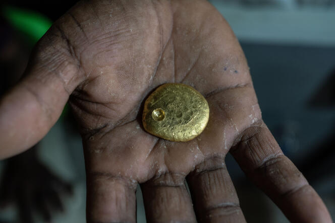 A buyer holds a piece of gold weighing about 75 grams in the souk of Al-Abidiyah, Sudan, on March 23, 2022