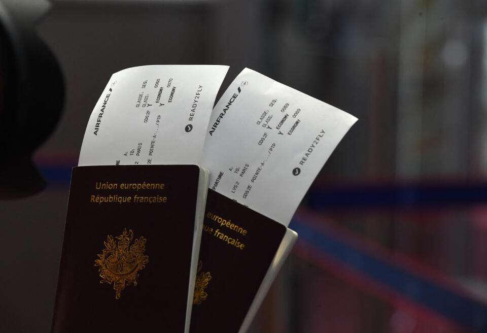 Passengers hold their passports with Air France travel documents with the 'ready to fly' health documentation at Roissy Charles de Gaulle Airport, north of Paris on July 20, 2021. (Photo by Eric PIERMONT / AFP)