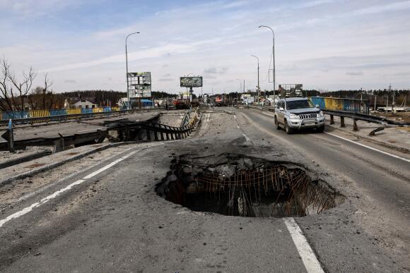 A vehicle drives through a hole in a damaged bridge on the outskirts of kyiv on April 8, 2022.