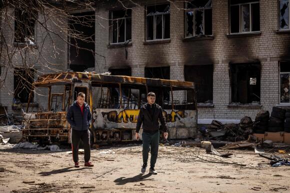 Men near a burned bus and a destroyed school in Borodianka on April 14, 2022.