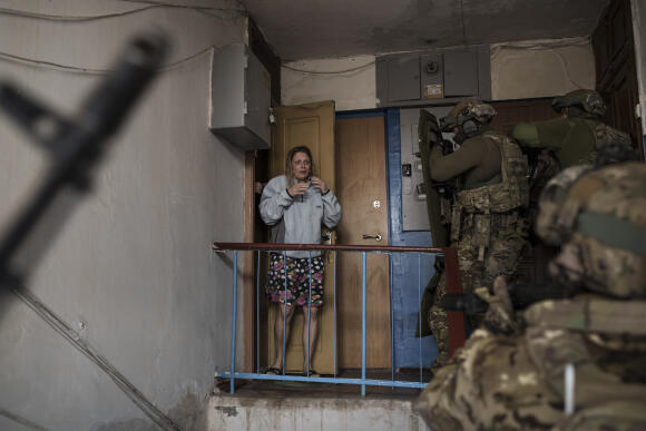 A woman watches soldiers from the Security Service of Ukraine (SBU) enter a building during an operation to arrest suspected Russian collaborators in Kharkiv, Thursday, April 14, 2022.