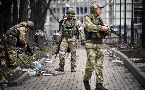Des soldats russes marchent dans une rue de Marioupol, le 12 avril 2022, alors que les troupes russes intensifient leur campagne pour prendre la ville portuaire stratégique, dans le cadre d’un assaut massif prévu dans l’est de l'Ukraine, tandis que le président russe défend la guerre contre son voisin.