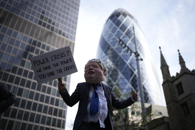 Un membre d’Extinction Rebellion porte un masque à l’effigie du premier ministre britannique, Boris Johnson, dans le quartier financier de la City, à Londres, le 12 avril 2022.