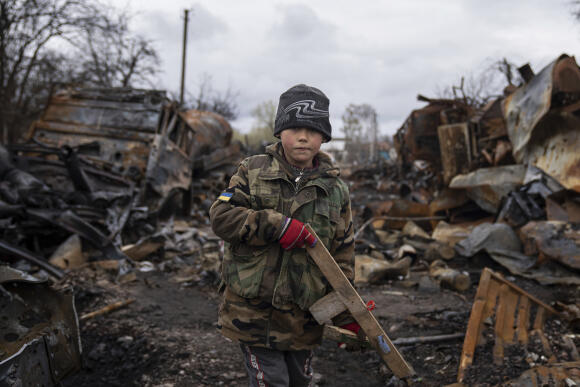 Iehor, 7 ans, tient un fusil en bois à côté de véhicules militaires russes détruits près de Tchernihiv, dimanche 17 avril 2022.