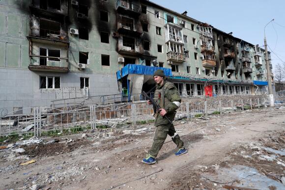 Un membre des troupes pro-russes passe devant un bâtiment résidentiel incendié pendant le conflit entre l'Ukraine et la Russie dans la ville portuaire de Mariupol, au sud de l'Ukraine, le 17 avril 2022.
