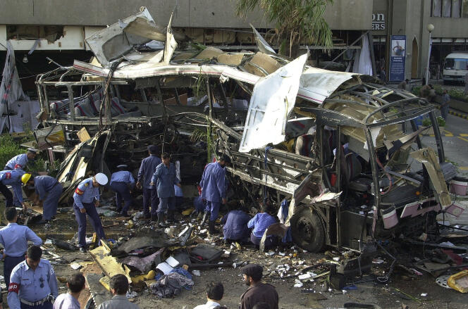 Des responsables de la sécurité pakistanaise examinent le bus totalement détruit après l’explosion d’une bombe devant l’hôtel Sheraton dans la ville portuaire de Karachi, dans le sud du Pakistan, le 8 mai 2002.