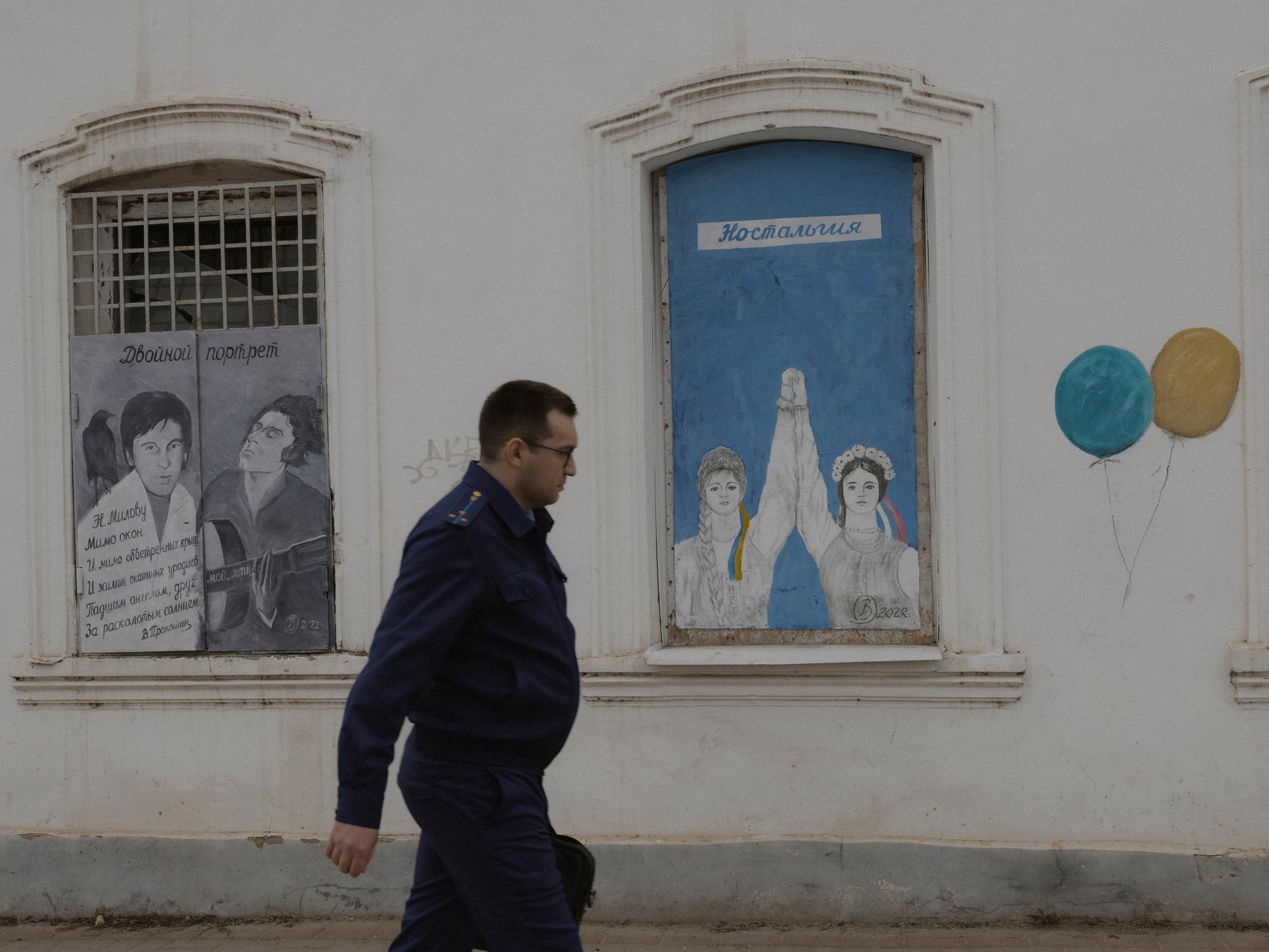 Le procureur local devant un graffiti de l'artiste Vladimir Ovtchinnikov qui appelle à la fraternité entre les peuples russes et ukrainiens.