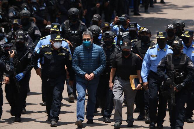 L’ancien président du Honduras, Juan Orlando Hernandez, est escorté par des membres de la police nationale, alors qu’ils se dirigent vers un hélicoptère qui le transportera vers la base aérienne Hernan Acosta Mejia, en vue de son extradition vers les États-Unis, le 21 avril 2022. 