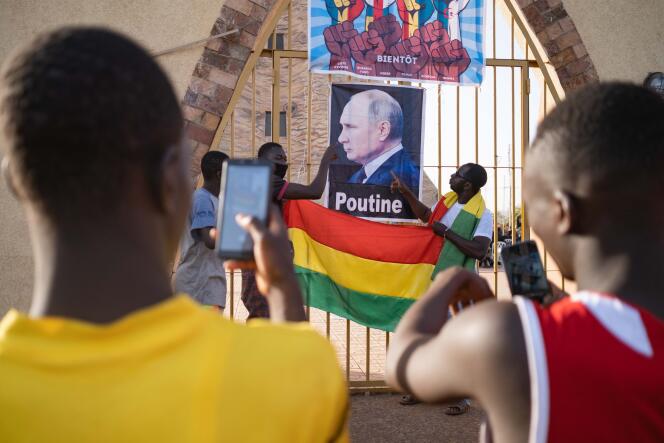 Des jeunes se prennent en photo devant une affiche du président russe Vladimir Poutine, lors de la manifestation portée par le mouvement Yerewolo contre la présence militaire française au Mali, place de la Tour de l’Afrique, à Bamako, le 4 février 2022.