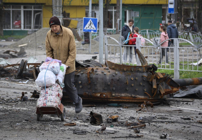 Άνθρωποι περπατούν κοντά σε ένα κατεστραμμένο στρατιωτικό όχημα σε μια περιοχή που ελέγχεται από τις υποστηριζόμενες από τη Ρωσία αυτονομιστικές δυνάμεις, στη Μαριούπολη της Ουκρανίας, 23 Απριλίου 2022.