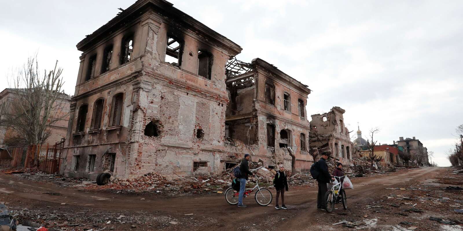 Des habitants passent près de bâtiments détruits  dans la ville portuaire du sud de Marioupol, en Ukraine, le 22 avril 2022. 