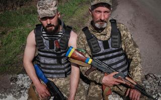 Ukrainian servicemen Vasyl, 51, and his son Denys, 22, (L) pose at a checkpoint near Barvinkove, eastern Ukraine, on April 25, 2022, amid the Russian invasion of Ukraine. (Photo by Yasuyoshi CHIBA / AFP)