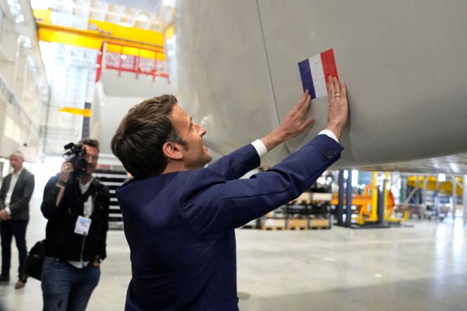 Emmanuel Macron sticks a French flag to a wind turbine at the Siemens Gamesa wind turbines factory during a visit as part of his campaign in Le Havre, western France, on April 14, 2022.