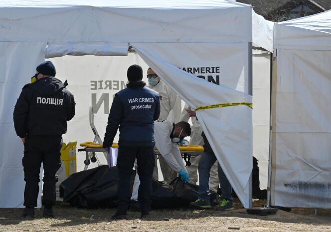Des enquêteurs français de l’Institut de recherche criminelle de la gendarmerie nationale (IRCGN) examinent un corps dans une tente, après son exhumation d’une fosse commune, à Boutcha, en Ukraine, le 14 avril 2022.