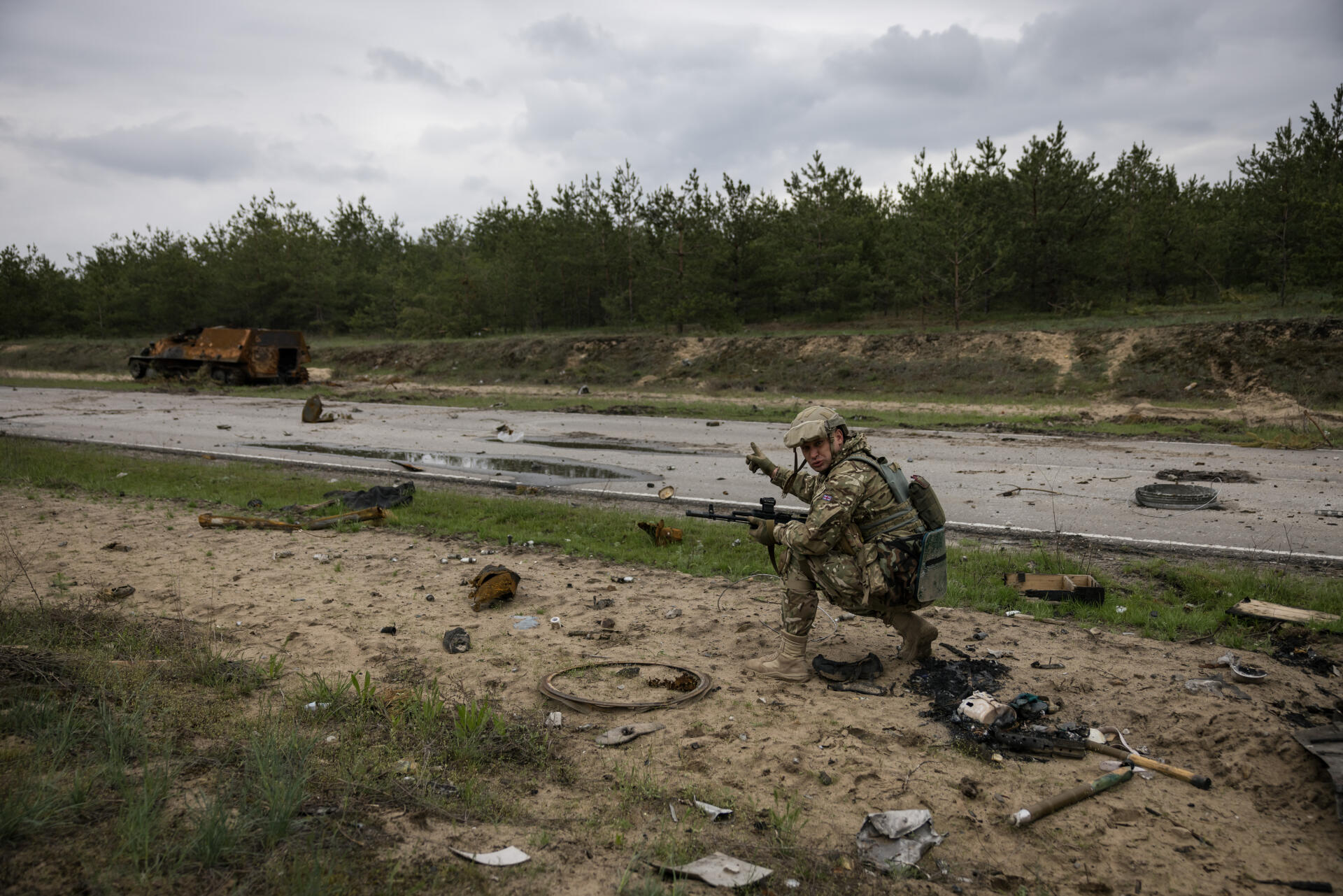 Un militaire ukrainien en première ligne sur le front, dans le Donbass (Ukraine), le 22 avril 2022. Au loin, un blindé russe carbonisé.