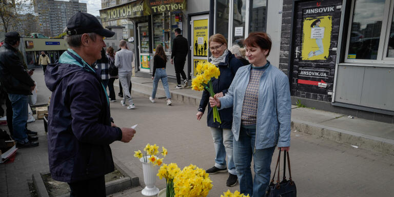Natalya Rastova achete des jonquilles à un marchand après avoir fait son marché dans le nord de Kiev en Ukraine, le 27 avril 2022.  LUCAS BARIOULET POUR «LE MONDE»