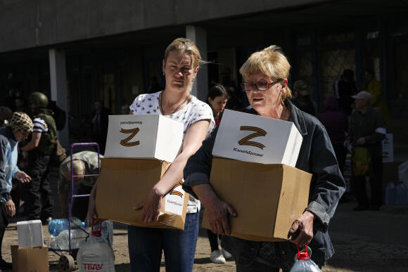 Deux femmes portent des cartons d’aide avec la lettre Z, qui est devenue un symbole de l’armée russe, et un hashtag indiquant « Nous n’abandonnons pas les nôtres ».