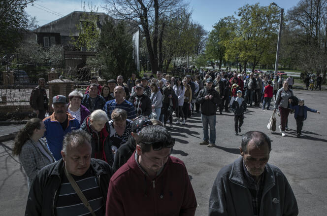 Residents of Kharkiv (Ukraine), where the vast majority of businesses are closed, wait for their turn to receive food distribution, on April 25, 2022