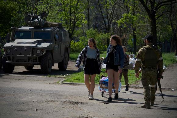 Des habitants sous l’œil des militaires de la République populaire de Donetsk autoproclamée qui gardent une zone, le 29 avril 2022.