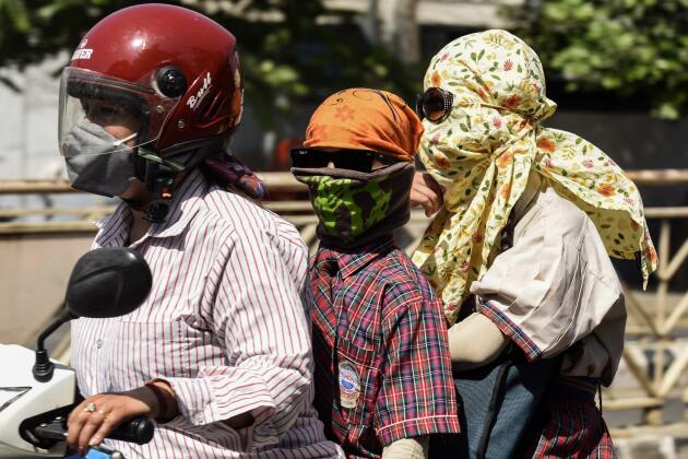 Motorcyclists cover their faces with a cloth to shelter from the heat, in Amritsar, Punjab state, on April 26, 2022. 