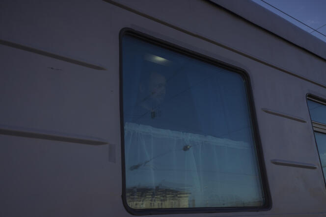 A man looks out of the window of the train connecting Belarus to the Russian enclave of Kaliningrad, during the stop in Vilnius station, on April 21, 2022. In front of the train, photos of the war in Ukraine are installed along the railings.