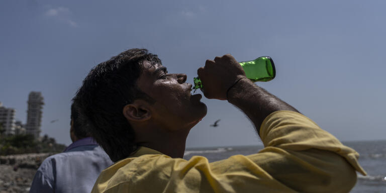 A boy drinks soda at a promenade on the Arabian Sea coast in Mumbai, India, Sunday, May 1, 2022. (AP Photo/Rafiq Maqbool)