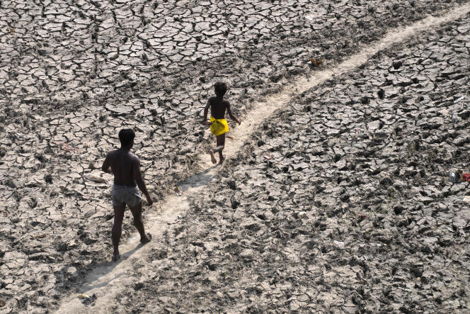 A man and a boy walk across an almost dried up bed of river Yamuna following hot weather in New Delhi, India, Monday, May 2, 2022. 