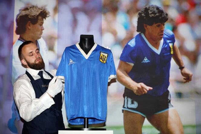 Le 20 avril 2022, un employé de Sotheby’s ajuste le maillot porté par Diego Maradona pendant la Coupe du monde de 1986. (Photo ADRIAN DENNIS / AFP)