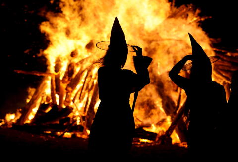 Two women dressed up as witches take pictures in front of the bonfire during the traditional San Juan's (Saint John) night on the beach in Gijon, northern Spain, June 24, 2015. Fires formed by burning unwanted furniture, old school books, wood and effigies of malign spirits are seen across Spain as people celebrate the night of San Juan, a purification ceremony coinciding with the summer solstice. REUTERS/Eloy Alonso