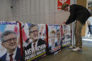 A supporter of far-left leader Jean-Luc Melenchon arranges electoral posters reading "Melenchon Prime Minister" before a local meeting, Thursday, May 5, 2022 in Lille, northern France. Jean-Luc Melenchon, who earned a third place finish in the presidential election, is trying to engineer a stunning comeback as the head of a coalition of leftist parties who have spent the past five years in the president's large shadow. Legislative elections will be held over two rounds of voting, on June 12 and 19.(AP Photo/Michel Spingler)