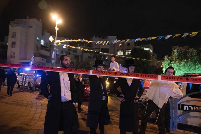 Ultra-Orthodox Jews stand behind police tape after a stabbing attack in the town of Elad, Israel, Thursday, May 5, 2022.