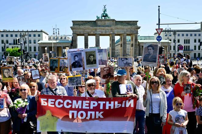Des proches de soldats soviétiques morts durant la seconde guerre mondiale brandissent les portraits de ces derniers et une banderole sur laquelle est inscrit « régiment immortel », devant la porte de Brandbourg, à Berlin, en Allemagne, le 9 mai 2022.