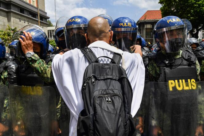 Un prêtre tente de discuter avec des policiers, devant la commission électorale, à Manille, le 10 mai 2022.