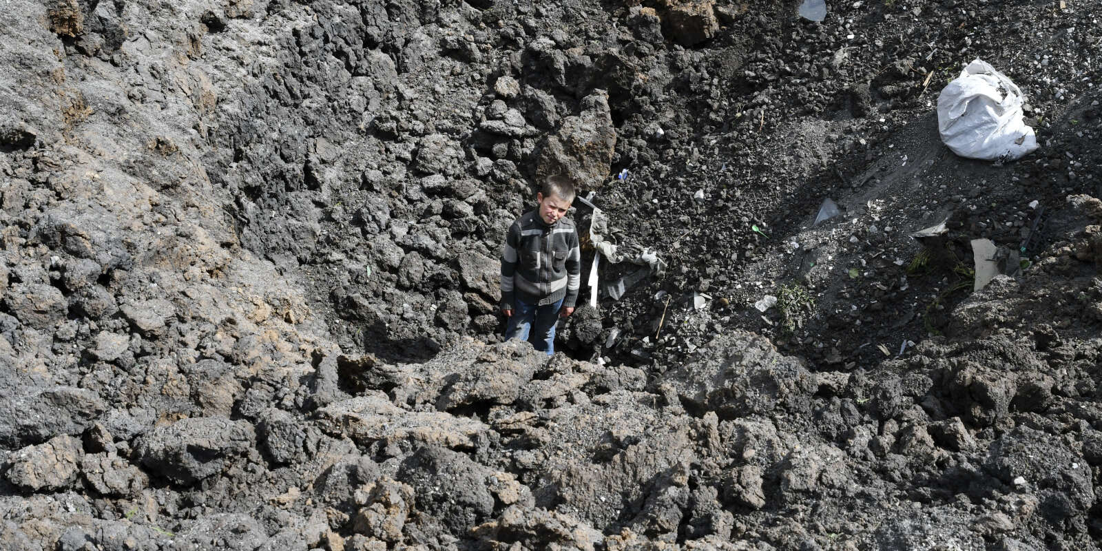 Maxim, un jeune garçon, se tient dans le cratère d’une explosion après un bombardement russe près de Sloviansk, dans la région ukrainienne de Donetsk, le 10 mai 2022.