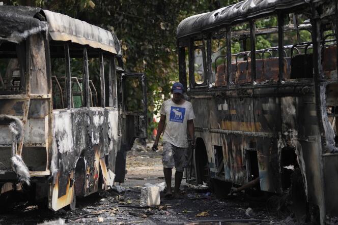 Un recogedor de chatarra de Sri Lanka busca artículos reciclables cerca de los autobuses que fueron quemados durante los enfrentamientos entre partidarios del gobierno y manifestantes antigubernamentales, en Colombo, Sri Lanka, el 11 de mayo de 2022.
