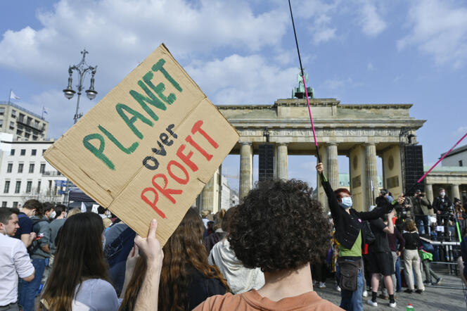 Des jeunes manifestent pour le climat et la justice sociale, avec une pancarte « La planète avant le profit », lors d’une marche organisée par le mouvement Fridays for Future, le 25 mars 2022, à Berlin.