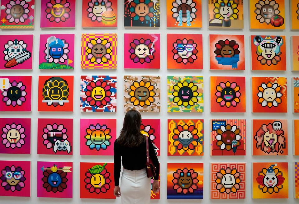 A person stands in front of artist Takashi Murakami’s NFT project called Murakami Flowers during a press preview May 11, 2022 for “An Arrow through History” at Gagosian’s New York galleries. This will be Murakami's first exhibition at Gagosian in New York since 2014 and represents his return to 980 Madison Avenue, where he had his inaugural exhibition with the gallery in 2007. - RESTRICTED TO EDITORIAL USE - MANDATORY MENTION OF THE ARTIST UPON PUBLICATION - TO ILLUSTRATE THE EVENT AS SPECIFIED IN THE CAPTION (Photo by TIMOTHY A. CLARY / AFP) / RESTRICTED TO EDITORIAL USE - MANDATORY MENTION OF THE ARTIST UPON PUBLICATION - TO ILLUSTRATE THE EVENT AS SPECIFIED IN THE CAPTION