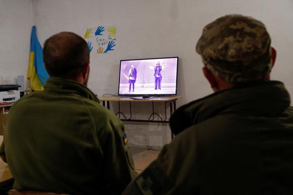 Près de Kiev, des engagés ukrainiens regardent la performance du groupe Kalush Orchestra lors de la finale de l’Eurovision. (Photo REUTERS/Valentyn Ogirenko)