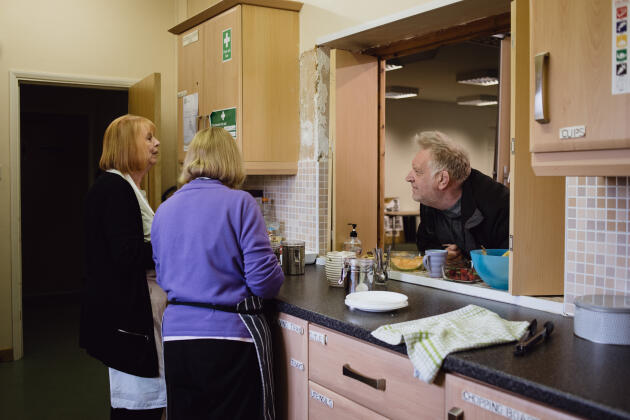 Des volontaires de l’église baptiste de Radcliffe servent un café à un homme, en marge d’une distribution alimentaire, le 6 mai 2022. 