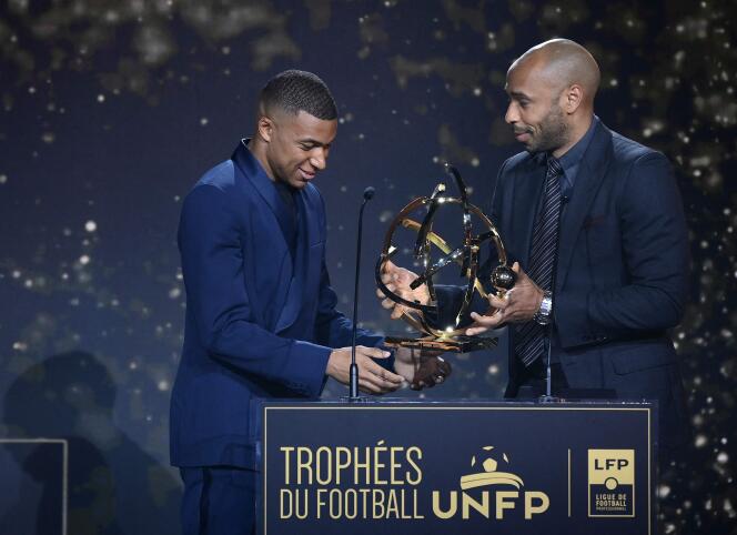 PSG striker Kylian Mbappé receives the UNFP trophy for the best player in Ligue 1 from Thierry Henry on May 15, 2022, in Paris.
