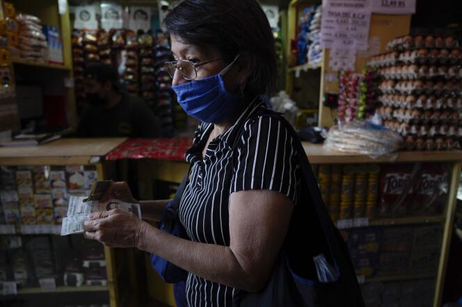 Une femme change des bolivars contre des dollars américains dans un petit magasin de Caracas, au Venezuela, le jeudi 12 mai 2022. 